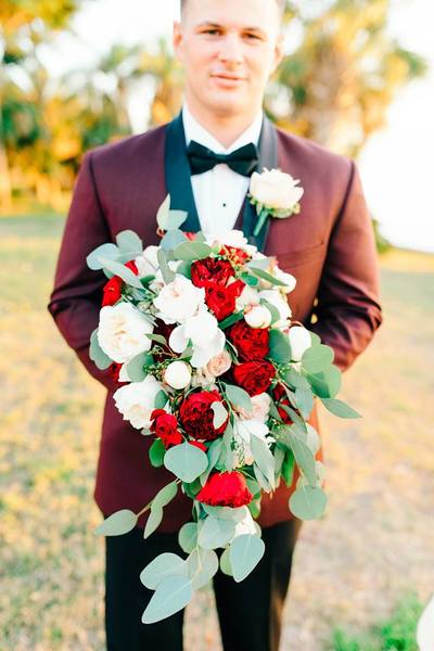 Cascading bridal bouquet featuring burgundy garden roses, champagne roses, white peonies, eucalyptus |  Groom burgundy tuxedo